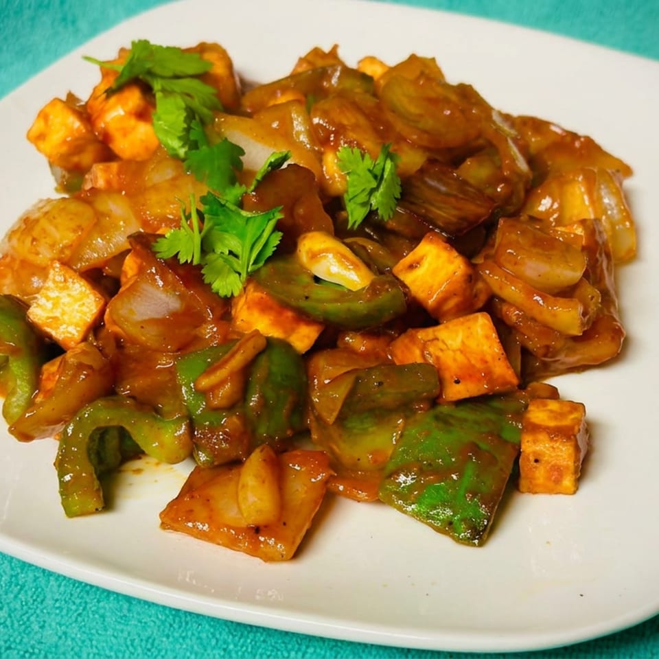 Spicy paneer stir-fry with bell peppers, onions, and cilantro served on a white plate.